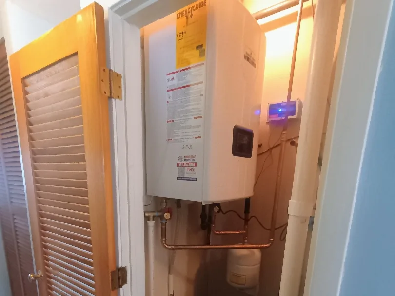 Newly installed tankless water heater with clean copper piping and expansion tank in a home utility closet