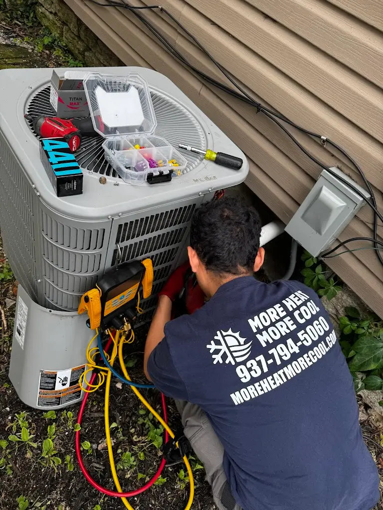 More Heat More Cool technician servicing an outdoor air conditioner