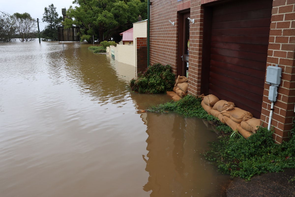 Sandbags stacked against a home's doorway as brown floodwater rises just outside