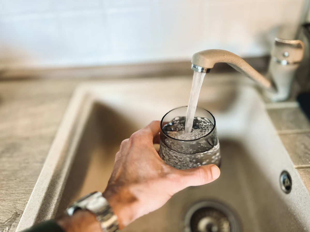 Glass being filled with clear water straight from the kitchen tap in a home with whole-home water treatment